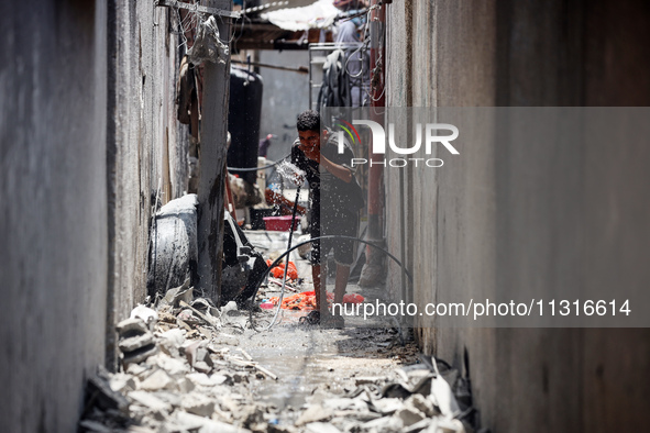 A Palestinian boy is pouring water over himself amidst a heatwave a day after an operation by the Israeli Special Forces in the Nuseirat cam...