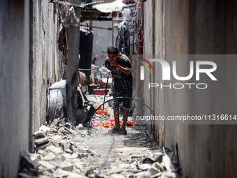 A Palestinian boy is pouring water over himself amidst a heatwave a day after an operation by the Israeli Special Forces in the Nuseirat cam...