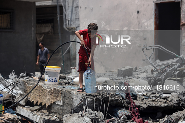 A boy is filling water a day after an operation by the Israeli Special Forces in the Nuseirat camp, in the central Gaza Strip, on June 9, 20...