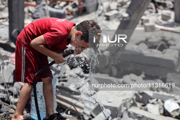 A Palestinian boy is pouring water over himself amidst a heatwave a day after an operation by the Israeli Special Forces in the Nuseirat cam...