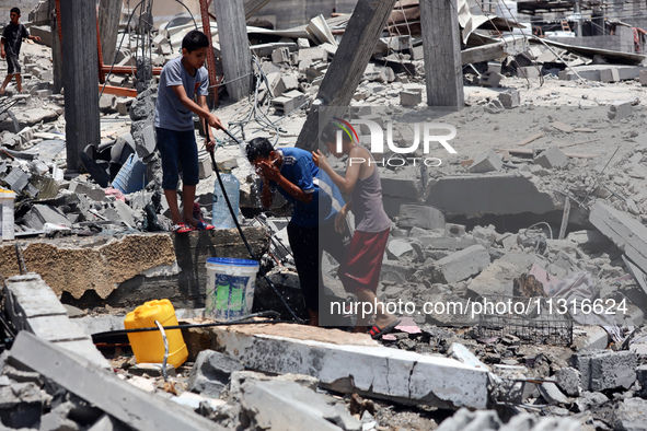 Palestinian children are playing with water amidst a heatwave a day after an operation by the Israeli Special Forces in the Nuseirat camp, i...