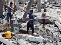 Palestinian children are playing with water amidst a heatwave a day after an operation by the Israeli Special Forces in the Nuseirat camp, i...