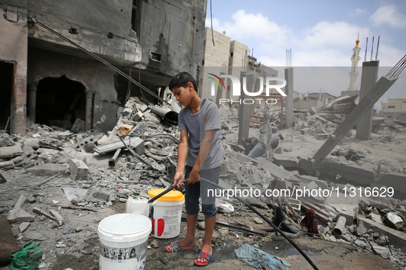 A boy is filling water a day after an operation by the Israeli Special Forces in the Nuseirat camp, in the central Gaza Strip, on June 9, 20...