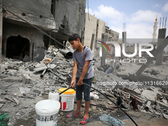 A boy is filling water a day after an operation by the Israeli Special Forces in the Nuseirat camp, in the central Gaza Strip, on June 9, 20...