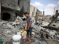 A boy is filling water a day after an operation by the Israeli Special Forces in the Nuseirat camp, in the central Gaza Strip, on June 9, 20...