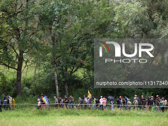 Protesters are walking near a wood. Nearly 5,000 people are participating in a weekend of action called 'Roue Libre' in the Tarn department...