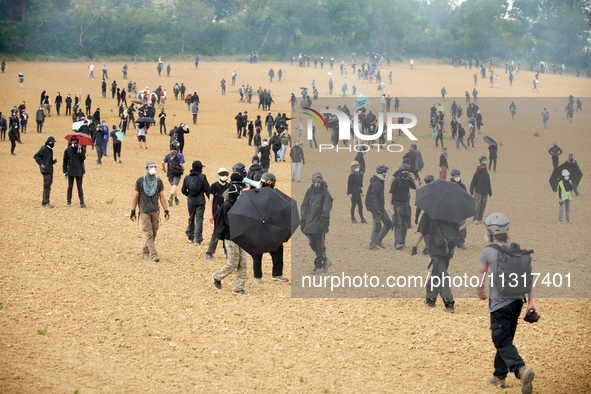 Black bloc is standing in a field during skirmishes with riot police. Nearly 5,000 people are participating in a weekend of action called 'R...