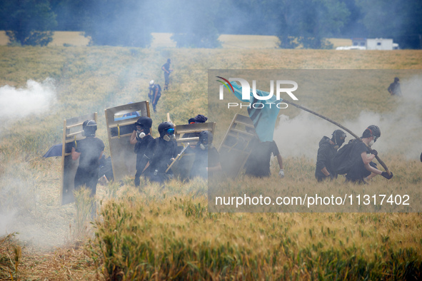 Black bloc is standing in a field of wheat during skirmishes with riot police. Nearly 5,000 people are participating in a weekend of action...