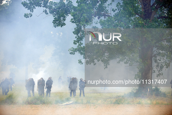 Riot policemen are standing amid clouds of tear gas. Nearly 5,000 people are participating in a weekend of action called 'Roue Libre' in the...