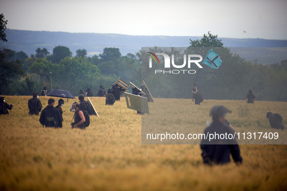 A black bloc is standing in a wheat field with the flag of the 'Soulevements de la Terre' (i.e., 'Earth Uprisings'). Nearly 5,000 people are...