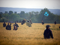 A black bloc is standing in a wheat field with the flag of the 'Soulevements de la Terre' (i.e., 'Earth Uprisings'). Nearly 5,000 people are...