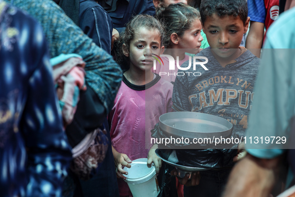 Palestinians are queuing for meal rations at a communal food distribution point in Deir al-Balah in the besieged Gaza Strip on June 10, 2024...