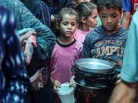 Palestinians are queuing for meal rations at a communal food distribution point in Deir al-Balah in the besieged Gaza Strip on June 10, 2024...