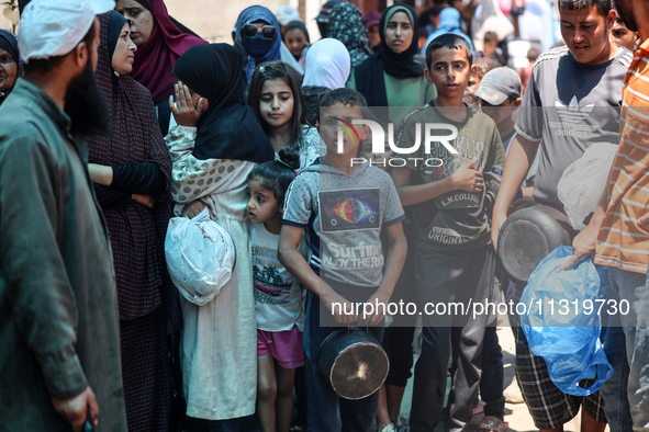 Palestinians are queuing for meal rations at a communal food distribution point in Deir al-Balah in the besieged Gaza Strip on June 10, 2024...