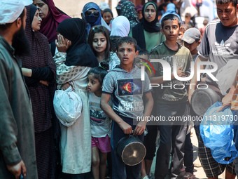 Palestinians are queuing for meal rations at a communal food distribution point in Deir al-Balah in the besieged Gaza Strip on June 10, 2024...