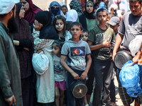 Palestinians are queuing for meal rations at a communal food distribution point in Deir al-Balah in the besieged Gaza Strip on June 10, 2024...