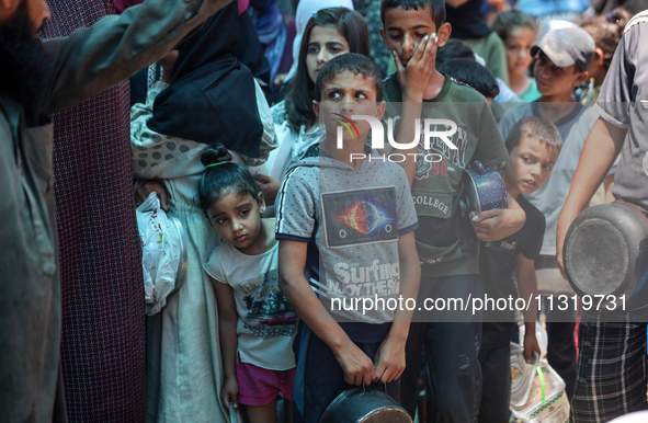 Palestinians are queuing for meal rations at a communal food distribution point in Deir al-Balah in the besieged Gaza Strip on June 10, 2024...