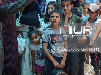 Palestinians are queuing for meal rations at a communal food distribution point in Deir al-Balah in the besieged Gaza Strip on June 10, 2024...