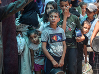 Palestinians are queuing for meal rations at a communal food distribution point in Deir al-Balah in the besieged Gaza Strip on June 10, 2024...