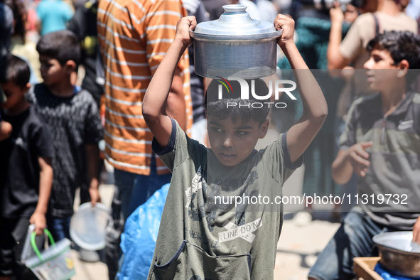 Palestinians are queuing for meal rations at a communal food distribution point in Deir al-Balah in the besieged Gaza Strip on June 10, 2024...