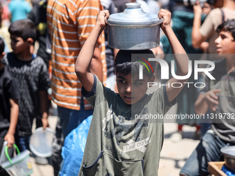 Palestinians are queuing for meal rations at a communal food distribution point in Deir al-Balah in the besieged Gaza Strip on June 10, 2024...