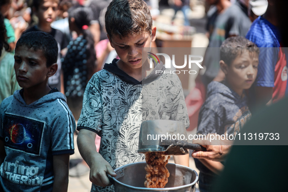 Palestinians are queuing for meal rations at a communal food distribution point in Deir al-Balah in the besieged Gaza Strip on June 10, 2024...