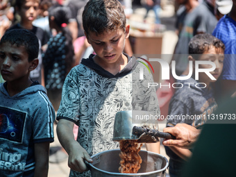 Palestinians are queuing for meal rations at a communal food distribution point in Deir al-Balah in the besieged Gaza Strip on June 10, 2024...