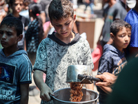 Palestinians are queuing for meal rations at a communal food distribution point in Deir al-Balah in the besieged Gaza Strip on June 10, 2024...