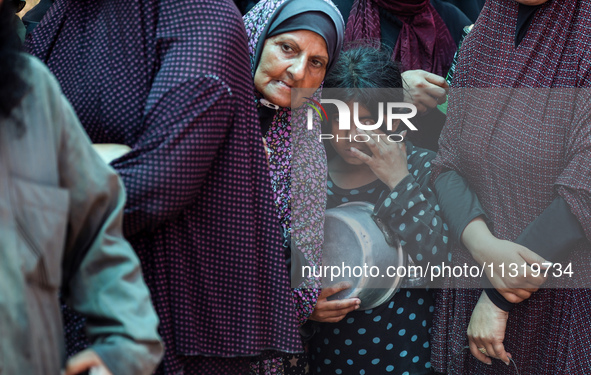 Palestinians are queuing for meal rations at a communal food distribution point in Deir al-Balah in the besieged Gaza Strip on June 10, 2024...