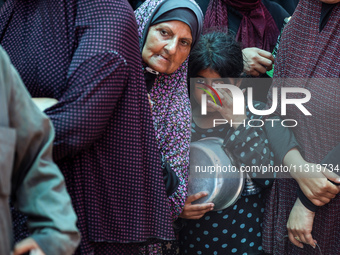 Palestinians are queuing for meal rations at a communal food distribution point in Deir al-Balah in the besieged Gaza Strip on June 10, 2024...