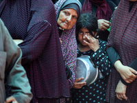 Palestinians are queuing for meal rations at a communal food distribution point in Deir al-Balah in the besieged Gaza Strip on June 10, 2024...