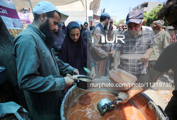 Palestinians are queuing for meal rations at a communal food distribution point in Deir al-Balah in the besieged Gaza Strip on June 10, 2024...