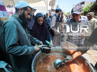 Palestinians are queuing for meal rations at a communal food distribution point in Deir al-Balah in the besieged Gaza Strip on June 10, 2024...