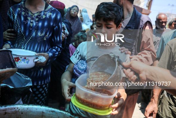 Palestinians are queuing for meal rations at a communal food distribution point in Deir al-Balah in the besieged Gaza Strip on June 10, 2024...