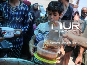 Palestinians are queuing for meal rations at a communal food distribution point in Deir al-Balah in the besieged Gaza Strip on June 10, 2024...