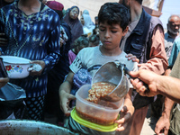 Palestinians are queuing for meal rations at a communal food distribution point in Deir al-Balah in the besieged Gaza Strip on June 10, 2024...