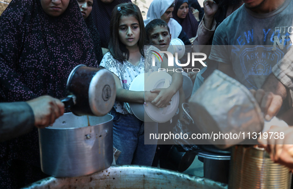 Palestinians are queuing for meal rations at a communal food distribution point in Deir al-Balah in the besieged Gaza Strip on June 10, 2024...