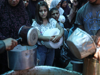 Palestinians are queuing for meal rations at a communal food distribution point in Deir al-Balah in the besieged Gaza Strip on June 10, 2024...