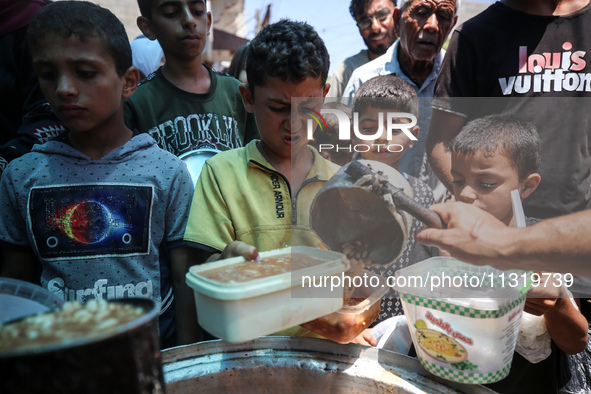 Palestinians are queuing for meal rations at a communal food distribution point in Deir al-Balah in the besieged Gaza Strip on June 10, 2024...