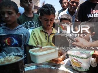 Palestinians are queuing for meal rations at a communal food distribution point in Deir al-Balah in the besieged Gaza Strip on June 10, 2024...