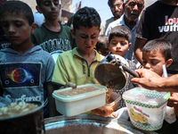 Palestinians are queuing for meal rations at a communal food distribution point in Deir al-Balah in the besieged Gaza Strip on June 10, 2024...