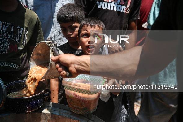 Palestinians are queuing for meal rations at a communal food distribution point in Deir al-Balah in the besieged Gaza Strip on June 10, 2024...