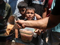 Palestinians are queuing for meal rations at a communal food distribution point in Deir al-Balah in the besieged Gaza Strip on June 10, 2024...