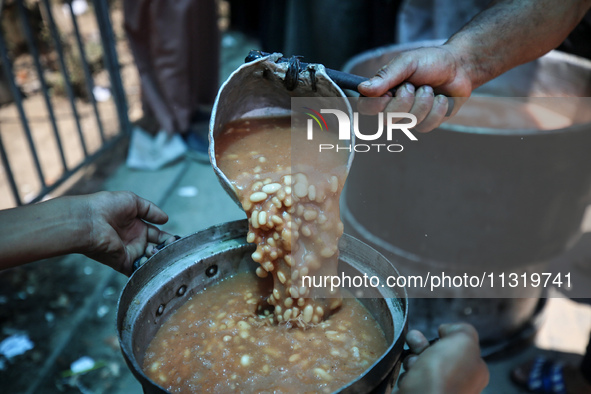 Palestinians are queuing for meal rations at a communal food distribution point in Deir al-Balah in the besieged Gaza Strip on June 10, 2024...