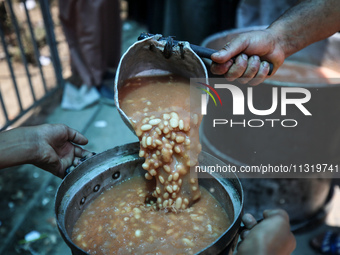 Palestinians are queuing for meal rations at a communal food distribution point in Deir al-Balah in the besieged Gaza Strip on June 10, 2024...