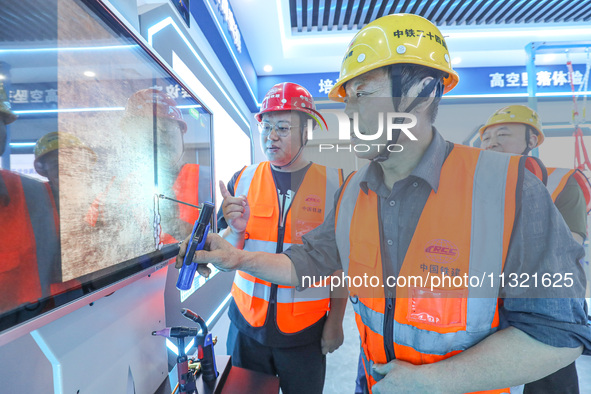 Workers are simulating the operation of an electric welding machine in Huzhou, China, on June 11, 2024. 