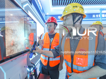 Workers are simulating the operation of an electric welding machine in Huzhou, China, on June 11, 2024. (