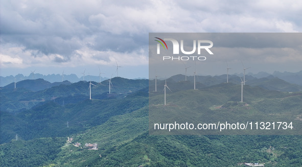 Wind turbines are being seen on a mountain in Qishe township in Xingyi city, Guizhou province, China, on June 11, 2024. 