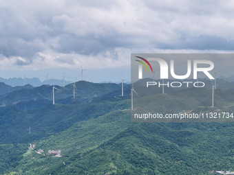 Wind turbines are being seen on a mountain in Qishe township in Xingyi city, Guizhou province, China, on June 11, 2024. (