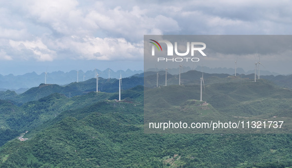 Wind turbines are being seen on a mountain in Qishe township in Xingyi city, Guizhou province, China, on June 11, 2024. 